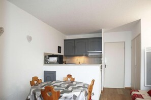 A compact kitchen with a microwave, cabinets, and a small island.