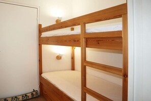 A bunk bed with a wooden frame and white bedding.