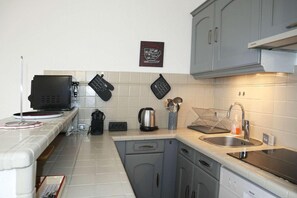A modern kitchen with grey cabinets, a built-in oven, a coffee machine, and a kettle.