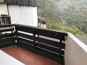 A balcony with a metal railing overlooking a forested valley.