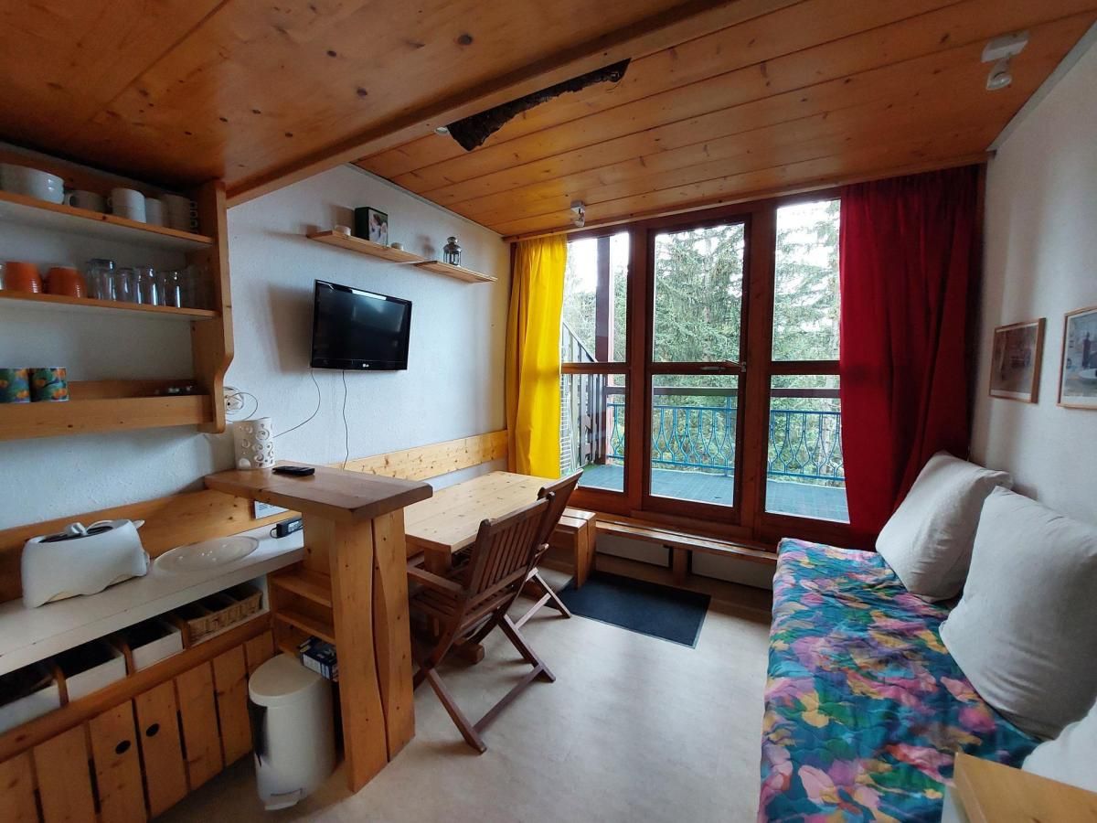 Una cabaña acogedora con interior de madera, comedor, sofá y televisor montado en la pared.