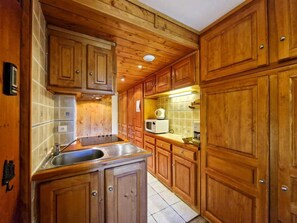 A kitchen with wooden cabinets, a stainless steel sink, and a microwave.
