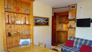 Ein Holzinnenraum mit Esstisch, Stühlen, einer Couch und einem Fernseher.