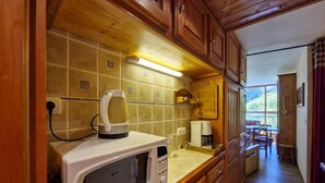 Eine Küche mit Holzausstattung, einer Mikrowelle und einer Kaffeemaschine.