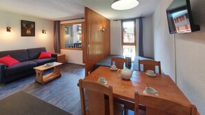 Una sala moderna con sofá, mesa de centro y mesa de comedor para dos.