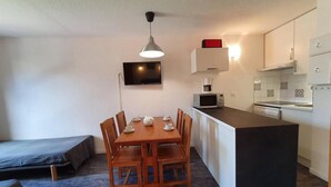 Un espacio habitable compacto con comedor, kitchenette y cama.