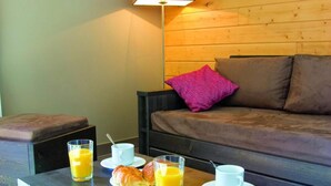 A cozy room with a wooden sofa, a coffee table with breakfast items, and a lamp. - 30m from resort center, swimming pool, sauna, hammam, terrace, balcony, tv, ski locker, 66m² (Font-Romeu-Odeillo-Via)