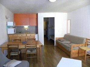 A compact living space with a kitchenette, a dining area, and a sofa.
