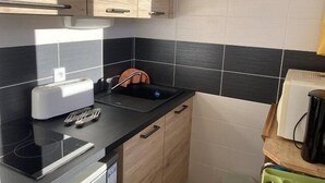 Een compacte keuken met een zwart aanrecht, een ingebouwde toaster, een spoelbak en een vaatwasser.