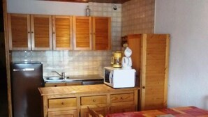 Eine kleine Küche mit Holzausstattung, einem Kühlschrank, einer Mikrowelle und einem Waschbecken.