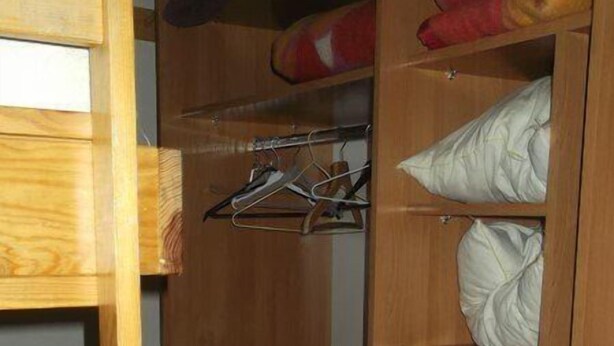 Ein Holzschrank mit Regalen und Kleiderstange, inklusive Bettgestell.