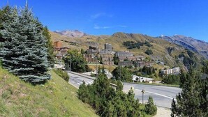 Un paese montano con edifici moderni, una strada e un grande abete sempreverde.