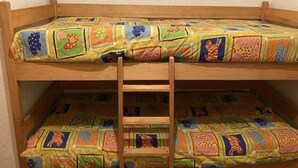 Un letto a castello con una coperta colorata e una scala in legno.