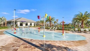 A pool area with water jets, palm trees, and lounge chairs. - Great Location! Disney-Universal-Kid Gear-Free Pool Heat-Lake view- Family Fun (Kissimmee)