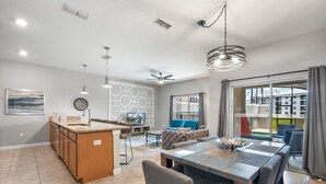 A modern kitchen with a central island, a dining area with a large table, and a living room with a sofa and TV. - Great Location! Disney-Universal-Kid Gear-Free Pool Heat-Lake view- Family Fun (Kissimmee)