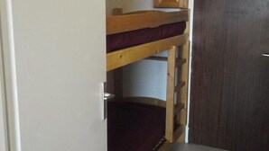 A bunk bed with a wooden frame and a red mattress, a wooden door, and a white wall. - 50m from ski slopes, 3rd floor, tv, 25m², Orcières Merlette 1850 (Orcières)
