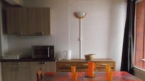 Eine kleine Küche mit Mikrowelle, Kaffeemaschine und einem Esstisch mit roter Tischdecke.