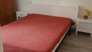 Ein Schlafzimmer mit einem Bett, einem Nachttisch, einer Lampe und einem Holzschrank.
