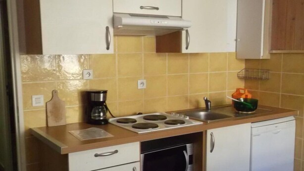 Cocina compacta con microondas, estufa y pileta. Hay gabinetes sobre la encimera y un horno pequeño debajo.