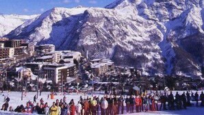 Ein mit Schnee bedeckter Berg mit einer Stadt im Hintergrund.