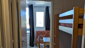 Ein Zimmer mit Etagenbetten, einem Esstisch und einer Couch.