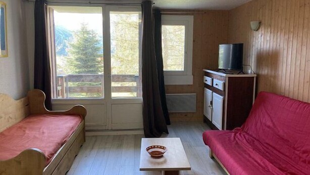 A room with a wooden interior, a bed, a sofa, a small table, a television on a cabinet, and a window with curtains. - 50m from ski slopes, 6th floor, tv, 45m², Orcières Merlette 1850 (Orcières)