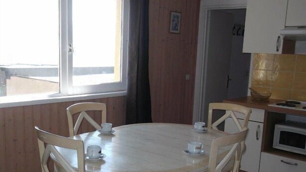 A dining area with a round table and four chairs, a window with a view, and a kitchen with a microwave and cabinets. - 200m from resort center, 1st floor, tv, 40m², Orcières Merlette 1850 (Orcières)