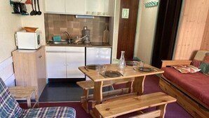 A compact living space with a kitchenette, a dining table with benches, a sofa, and a bed. - 50m from ski slopes, 7th floor, tv, 19m², Orcières Merlette 1850 (Orcières)