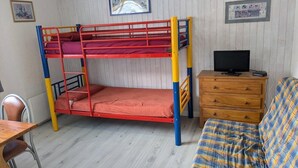 Una cama litera con televisión y cómoda en una habitación con paredes de madera.