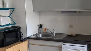 Una cocina compacta con microondas, lavabo y lavavajillas.