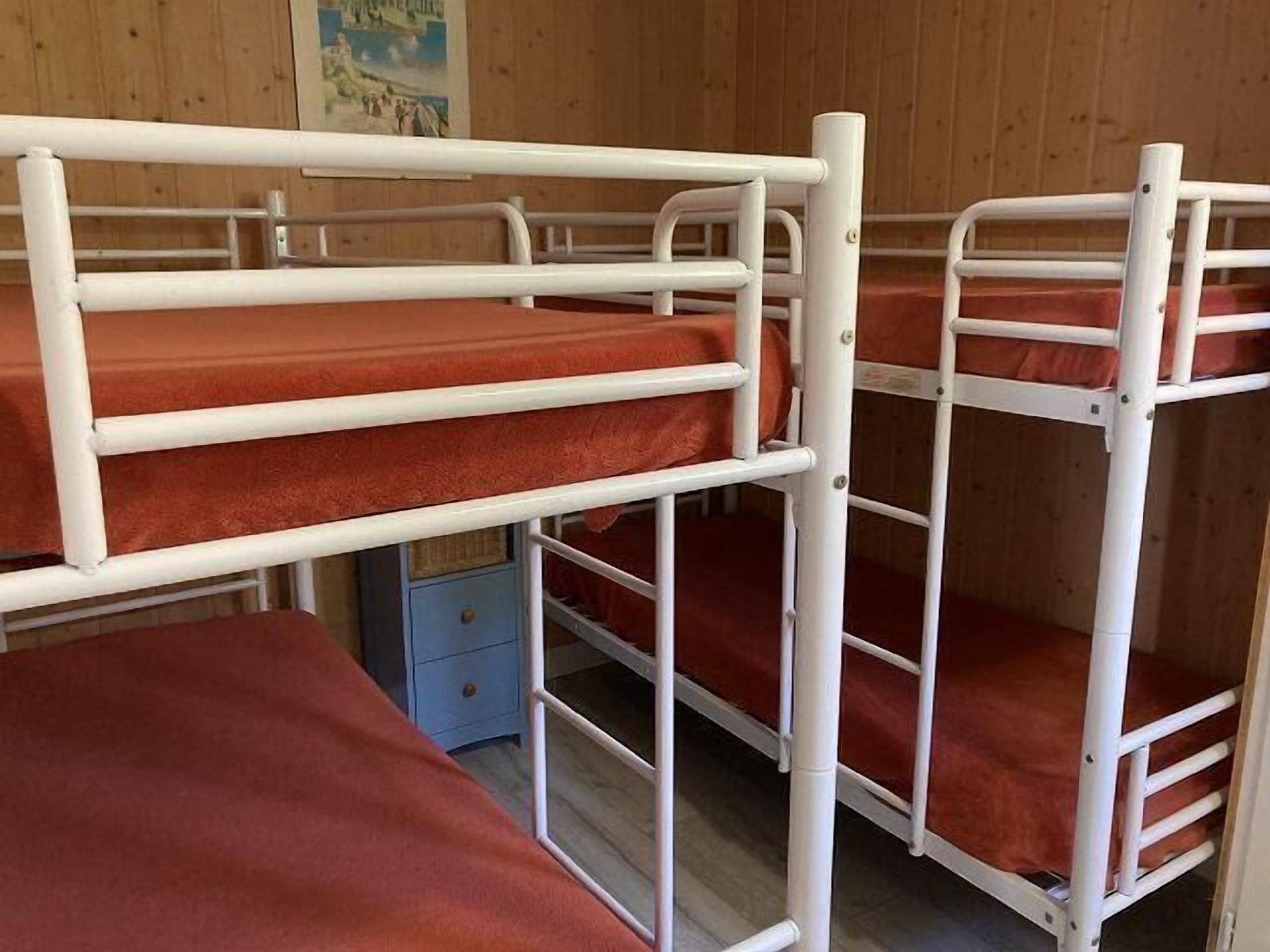 Habitación con literas, paredes de madera y un pequeño armario azul.