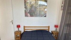 A bedroom with a wooden bed, two bedside tables with lamps, a door, and a wall-mounted artwork. - 50m from ski slopes, 1st floor, terrace, tv, 40m², Orcières Merlette 1850 (Orcières)