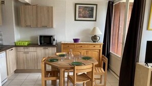 A compact kitchen with wooden cabinets, a microwave, and a dining table set for four.