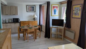 A compact kitchen with wooden cabinets, a microwave, a coffee maker, and a dining table with chairs.