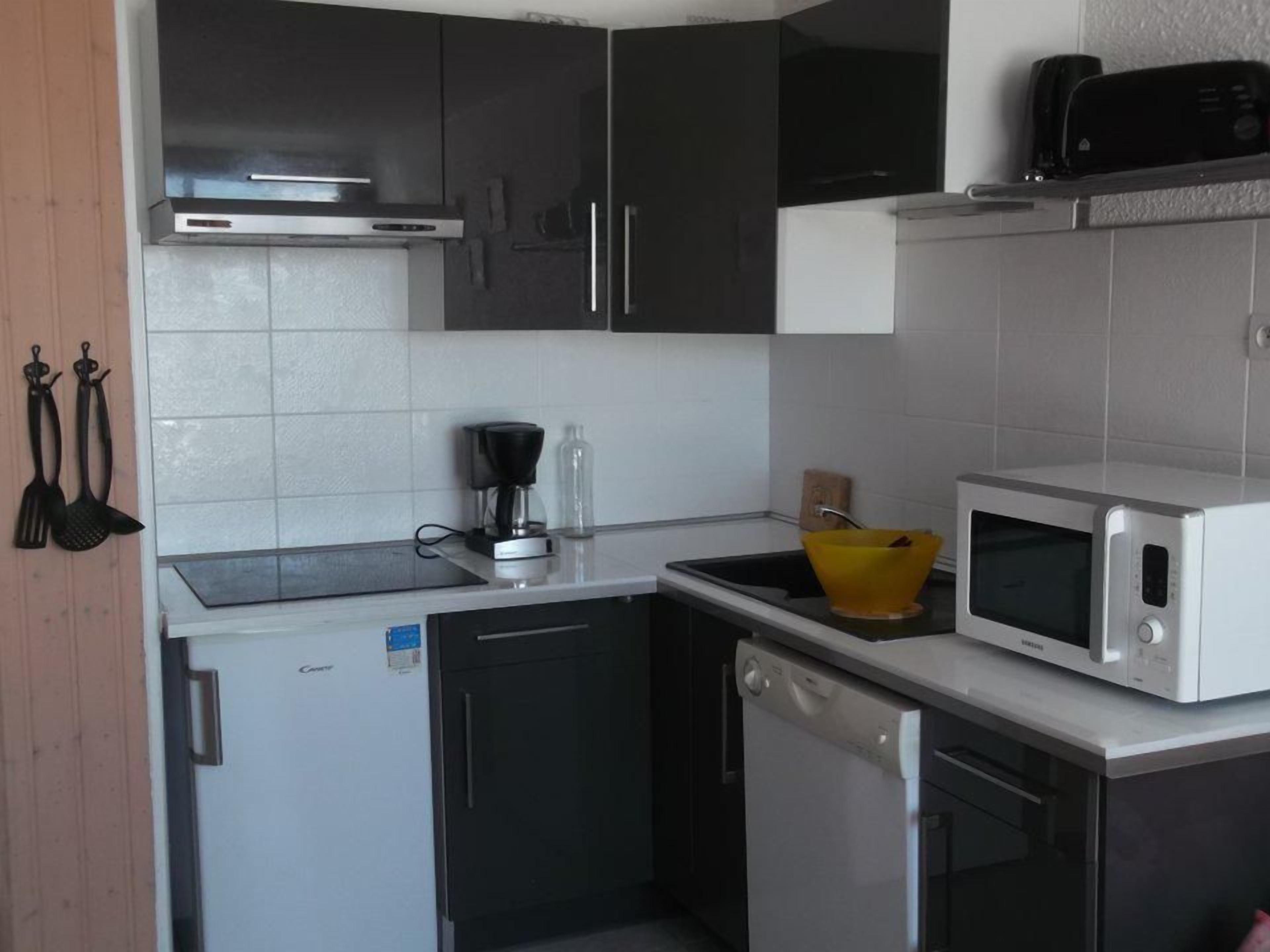 A compact kitchen with a dishwasher, microwave, and a coffee maker on the counter.