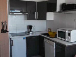 A compact kitchen with a dishwasher, microwave, and a coffee maker on the counter.