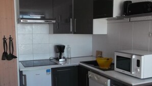A compact kitchen with a dishwasher, microwave, and a coffee maker on the counter.
