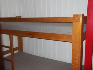 A bunk bed with a wooden frame and grey mattress.