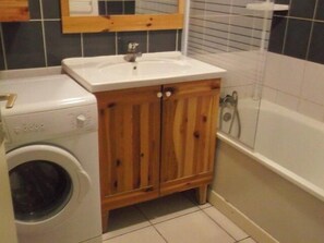 A compact bathroom with a washing machine, wooden cabinets, and a bathtub. - 200m from resort center, 1st floor, terrace, tv, 28m², Orcières Merlette 1850 (Orcières)