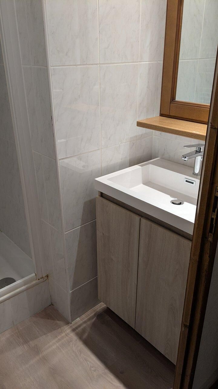 Ein Badezimmer mit einem weißen Waschbecken, Holzschränken und einem Spiegel.