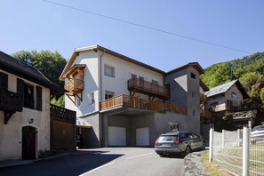 Un immeuble de deux étages doté d’un balcon, d’un garage et d’une voiture garée.