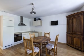 Une cuisine compacte comprenant une table et des chaises, un four encastré et un meuble en bois.