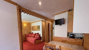 A cozy room with a bed, a dining table, and a TV.