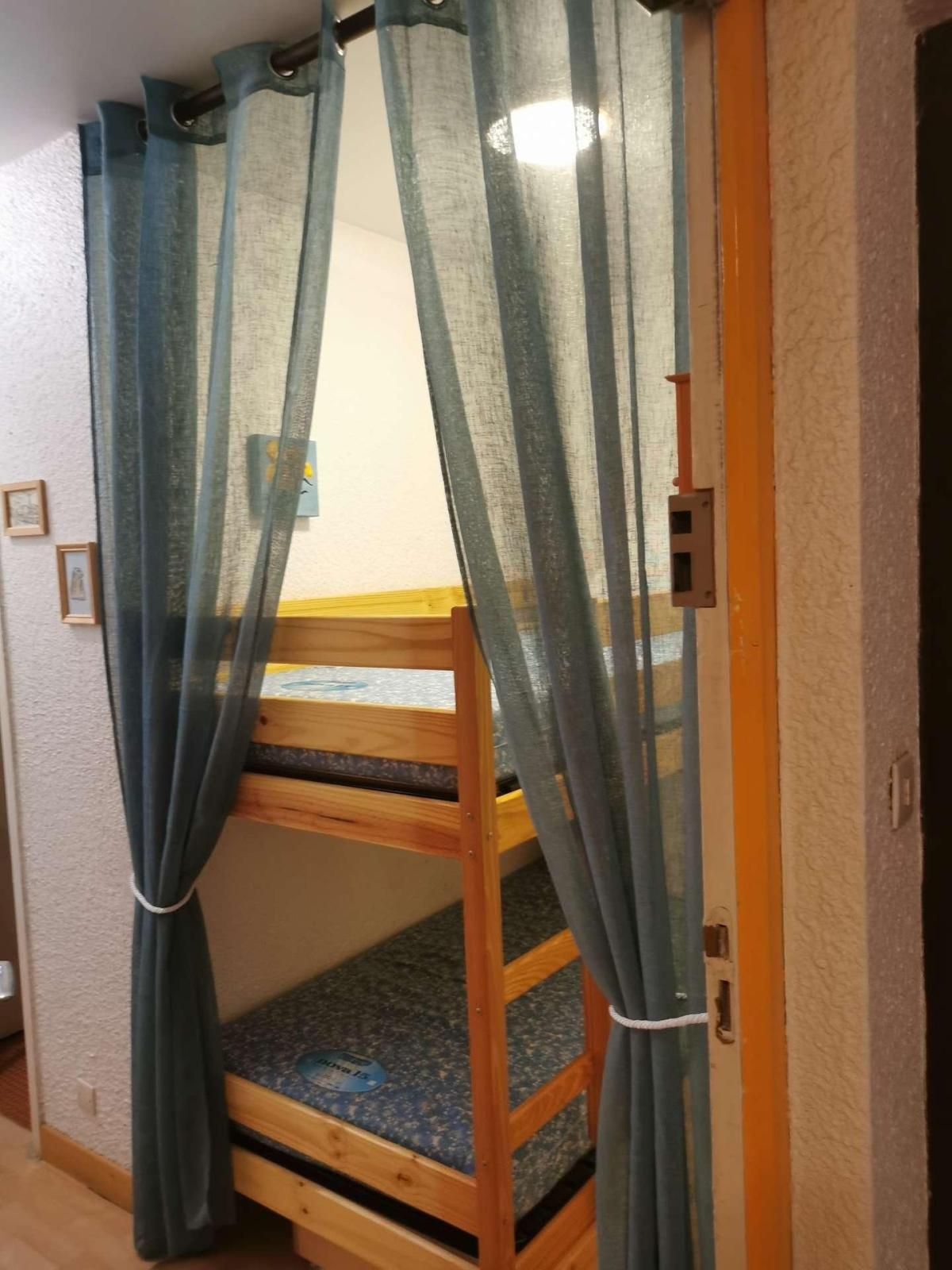 Ein Stockbett mit Holzrahmen und einer blauen Matratze.