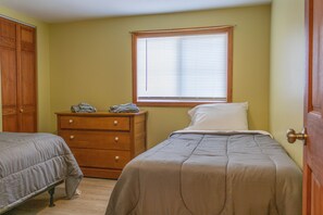 A bedroom with two beds, a wooden dresser, and a window with blinds. - Cozy Cottage On The Susquehanna River (Portlandville)