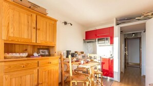 A compact kitchen with wooden cabinets, a dining table with chairs, and a red appliance. - 3rd floor, balcony, tv, 22m², La Rosière (La Rosière Montvalezan)