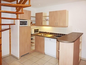 A compact kitchen with wooden cabinets, a microwave, a dishwasher, and a small countertop.