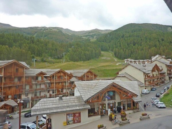 A mountain resort with wooden buildings, a central building with a ski lift, and a road leading to the parking area. - Ski-in/ski-out & foot of the slopes, 6th floor, swimming pool, sauna, balcony, tv, ski locker, 50m² (Les Orres)