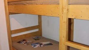 Un llit superposat amb estructura de fusta, un matalàs i un calaix a la part inferior.
