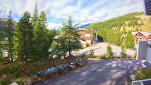 Un camino que lleva a un edificio rodeado de árboles y montañas.